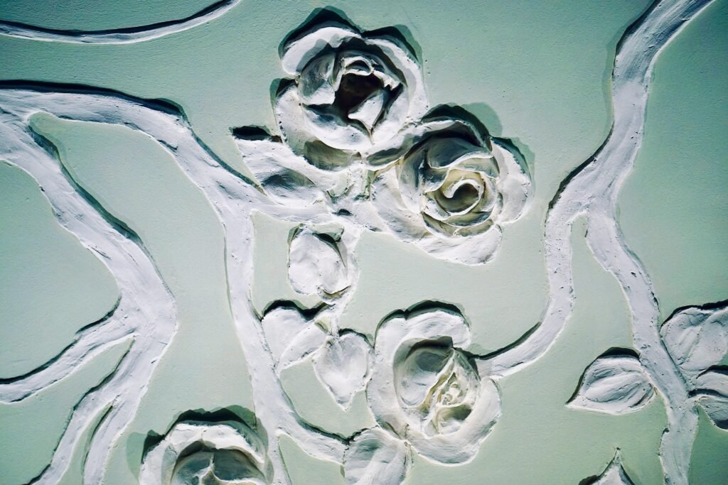 Intricate bas relief featuring elegant carved floral patterns and roses on a light green surface.